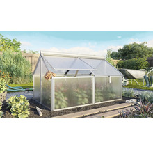 Aluminium broeibak met kanaalplaten in een zonnige tuin met tuingereedschap en planten op de achtergrond.