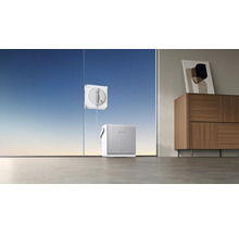 Een elektrische vensterreinigingsrobot reinigt een groot raam, verbonden met een basisstation op de vloer in een moderne kamer.
