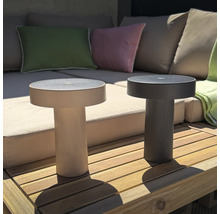 Twee ronde, moderne LED tafellampen met geribbelde voet op een houten terras voor een loungebank.