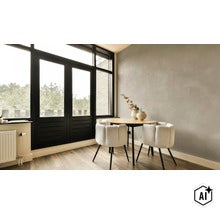 Woonruimte met ronde tafelset en twee stoelen voor een muur met decoratieve betonlook en een groot zwart raam. (Image AI modified or generated)