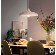 Moderne hanglamp boven een eettafel met een boeket bloemen en decoratie op de achtergrond in een lichte woonkamer. (Image AI modified or generated)