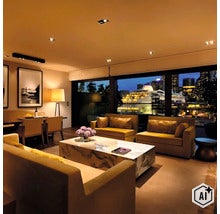 Luxe woonkamer met moderne banken, een marmeren salontafel en uitzicht op een cruiseschip in de haven bij nacht. (Image AI modified or generated)