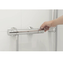 Hand bedient een Grohe thermostatische douchekraan aan een betegelde wand
