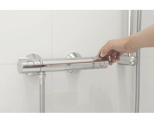 Hand bedient een Grohe thermostatische douchekraan aan een betegelde wand