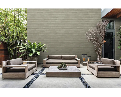 Moderne houten loungeset op een terras voor een bakstenen muur met plantenbak en loungetafel