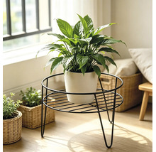 Een ronde metalen plantenstandaard met een lepelplant in een pot in een lichte woonomgeving.