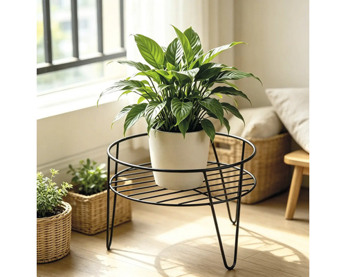 Een ronde metalen plantenstandaard met een lepelplant in een pot in een lichte woonomgeving.