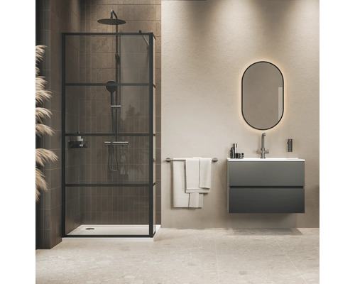 Moderne badkamer met inloopdouche met zwart frame, wandhangend wastafelmeubel, ovale verlichte spiegel en handdoekhouder.