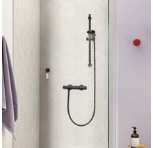 Douchesysteem met thermostaatkraan aan een muur met zeshoekige tegels in een moderne badkamer.