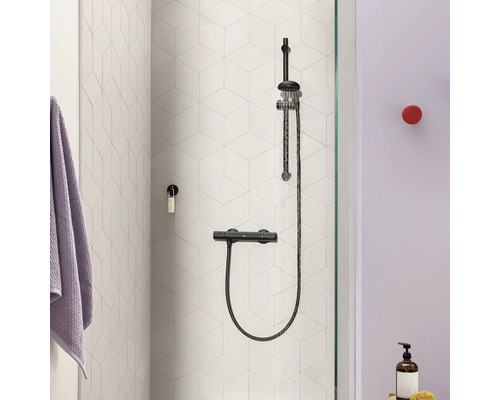 Douchesysteem met thermostaatkraan aan een muur met zeshoekige tegels in een moderne badkamer.