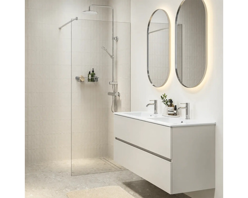 Moderne badkamer met inloopdouche, dubbele wastafel met onderkast en verlichte ovale wandspiegels in een licht interieur.