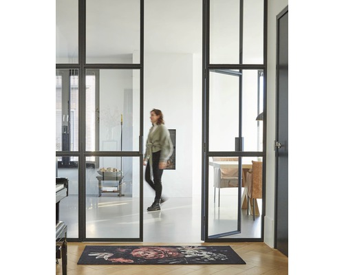 Lichte ruimte met stalen kozijndeur, vloerkleed en een vrouw