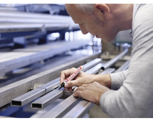 Ambachtman markeert een metalen profiel op een werkbank met een Edding 3000 permanente marker.