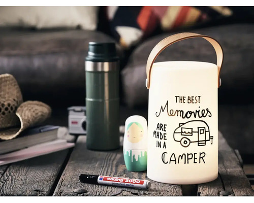 Een decoratieve lantaarn met draagbeugel en de tekst The Best Memories Are Made In A Camper op een houten tafel met een stift.