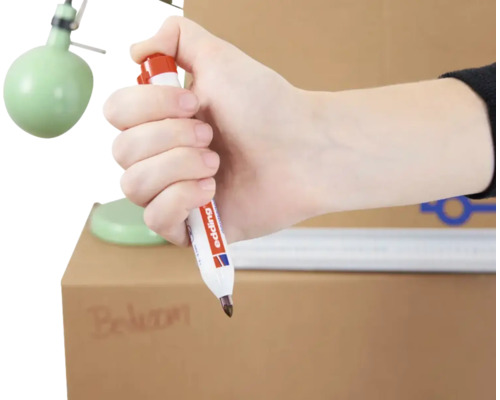 Hand houdt een Edding permanent marker vast voor het beschrijven van een doos