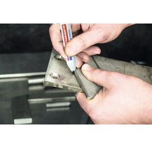 Een hand markeert een metalen plaat met een permanente marker tijdens metaalbewerking.