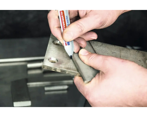 Een hand markeert een metalen plaat met een permanente marker tijdens metaalbewerking.