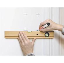Een hand houdt een houten waterpas tegen een muur terwijl de andere hand markeringen tekent met een Edding marker.
