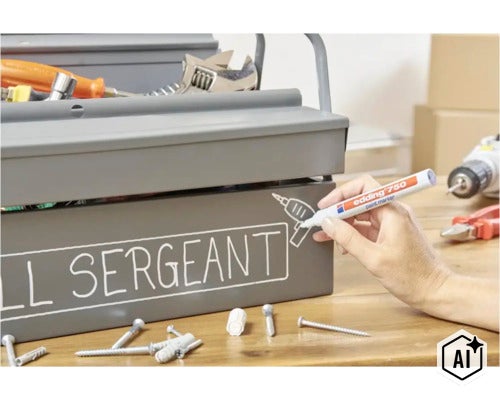 Een hand schrijft op een grijze metalen gereedschapskist met een Edding 750 lakmarker op een houten tafel. (Image AI modified or generated)