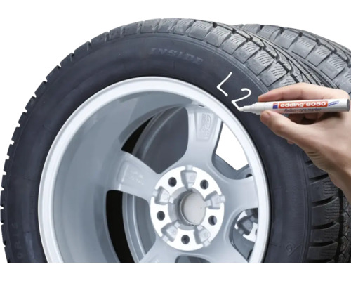 Een hand markeert een autoband met een Edding 8050 bandenmarker.