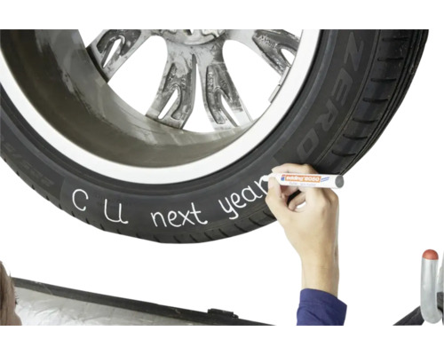 Hand schrijft op autoband met Edding 8050 bandenmarker