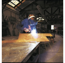 Een lasser bewerkt een metalen plaat met een Edding markeerstift in een industriële werkplaats.
