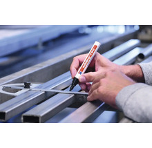 Een hand markeert een metalen buis met een Edding 750 lakmarker langs een winkelhaak.