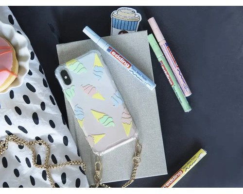 Transparant telefoonhoesje met ijsjespatroon en ketting naast drie Edding creatieve markers op een notitieblok.