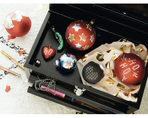 Een open zwarte gereedschapskist gevuld met verschillende kerstballen en twee Edding stiften voor decoratie.