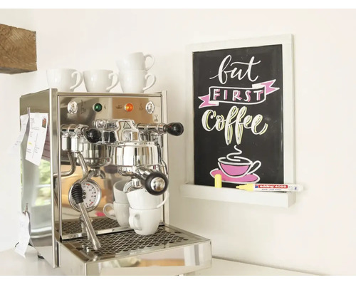 Roestvrijstalen espressomachine naast een wandbord met de tekst But First Coffee en een Edling krijtstift.