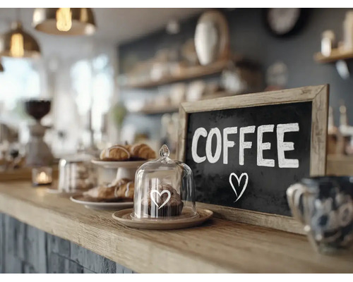 Een toonbank in een cafe met een krijtbord met de tekst Coffee en een kleine glazen stolp met gebak op de bar.