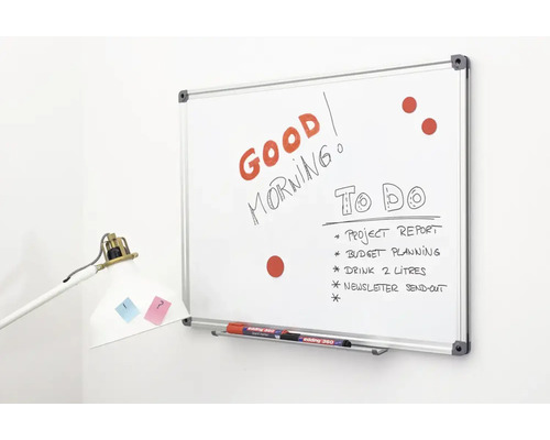 Een whiteboard met aluminium frame aan een muur, beschreven met tekst en taken, inclusief pennenbakje en stiften.