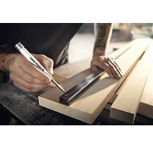Vakman markeert boorgaten met een Edding 8880 diepgatmarker door een metalen profiel op een houten plank.