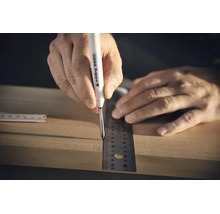 Een hand gebruikt een Edding 8880 diepgatmarker en een liniaal om een markering op een houten plank te maken.