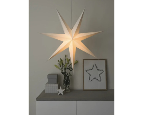 Verlichte papieren ster als hanglamp gedecoreerd op een dressoir met vaas en decoratieve objecten.