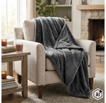 Een zachte fleece deken gedrapeerd over een fauteuil in een gezellige woonkamer met open haard. (Image AI modified or generated)