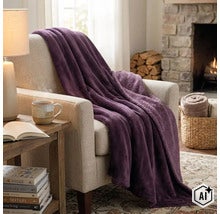 Een zachte plaid ligt gedrapeerd over een gestoffeerde fauteuil in een woonkamer met open haard. (Image AI modified or generated)