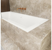 Moderne inbouwbadkuip met inbouwkraan in een badkamer met natuursteen bekleding in marmerlook.