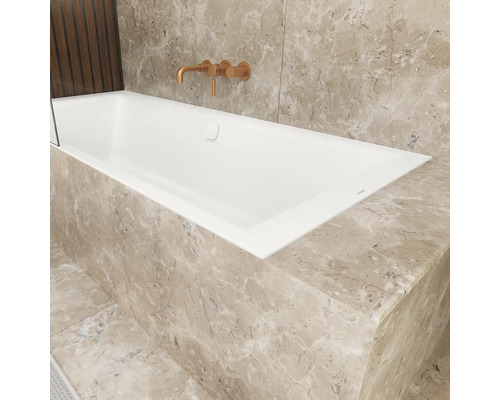 Moderne inbouwbadkuip met inbouwkraan in een badkamer met natuursteen bekleding in marmerlook.