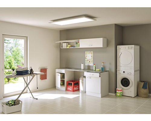 Lichte wasruimte met wasmachine, droger, strijkplank, wandkasten en verlichting