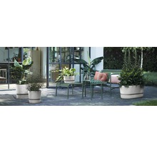 Buitenruimte met planten in plantenbakken op een terras met zitplaatsen.