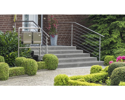 Buitenfoto van een huisentree met trap, roestvrijstalen leuning en twee brievenbussen voor een verzorgde tuin.