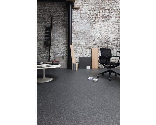 Interieur met donkere vloerbedekking, bureaustoel en witte tafel voor een bakstenen muur