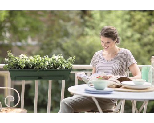 Vrouw leest op balkon met balkonbak en gedekte tafel