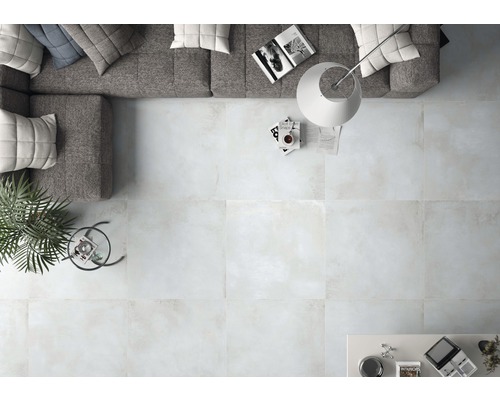 Lichte woonkamer met tegelvloer, bank, vloerlamp en tafel