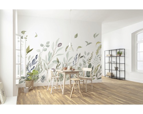 Lichte eetkamer met muursticker met bladerenmotief, houten tafel en stoelen