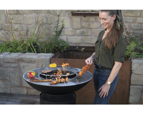 Vrouw grilt met een vuurplaats in de tuin.