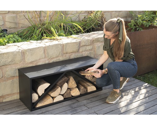 Vrouw legt hout in een zwart houtrek in de tuin