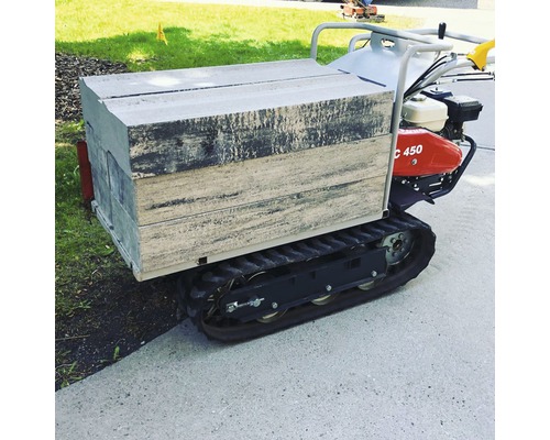 Rupsdumper met gevulde bak voor het vervoer van bouwmaterialen in de tuin