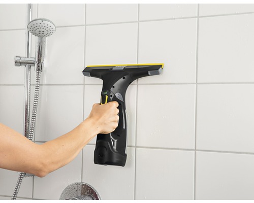 Hand gebruikt raamwisser op badkamerwandtegels